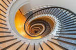 A helical staircase with wooden treads and carpet runner